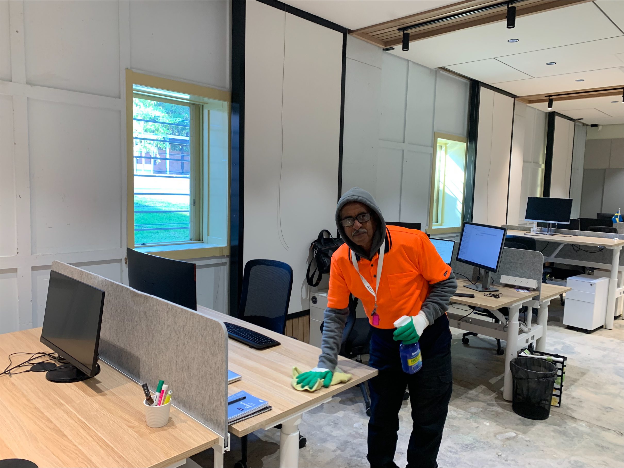 Yohannes Melak Habte cleaning the Witton office wearing a hi-viz orange workshirt