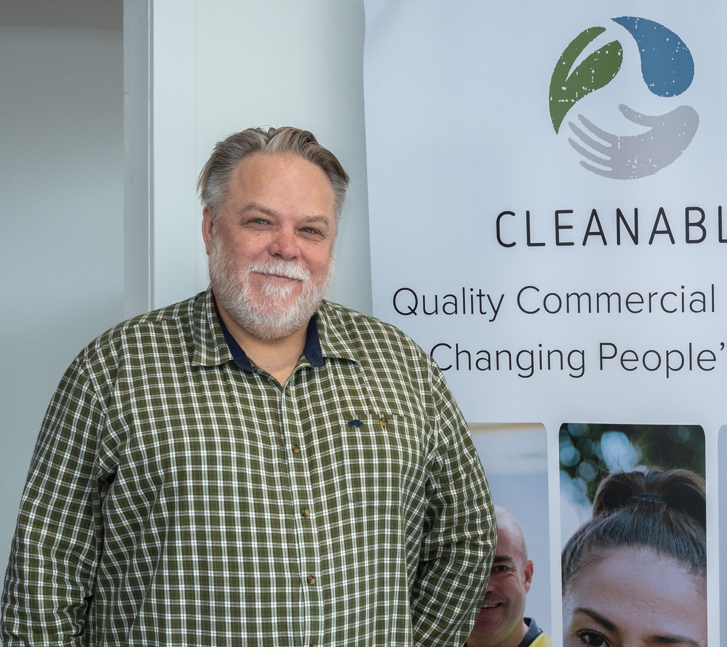 Man in check shirt standing in front of Cleanable banner