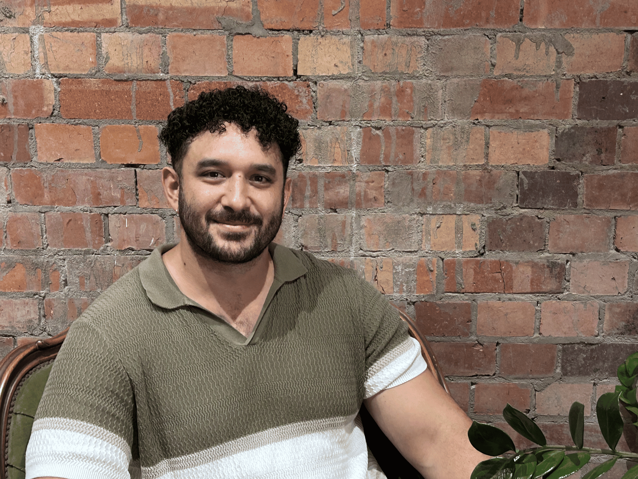 Man sitting and smiling against brick wall